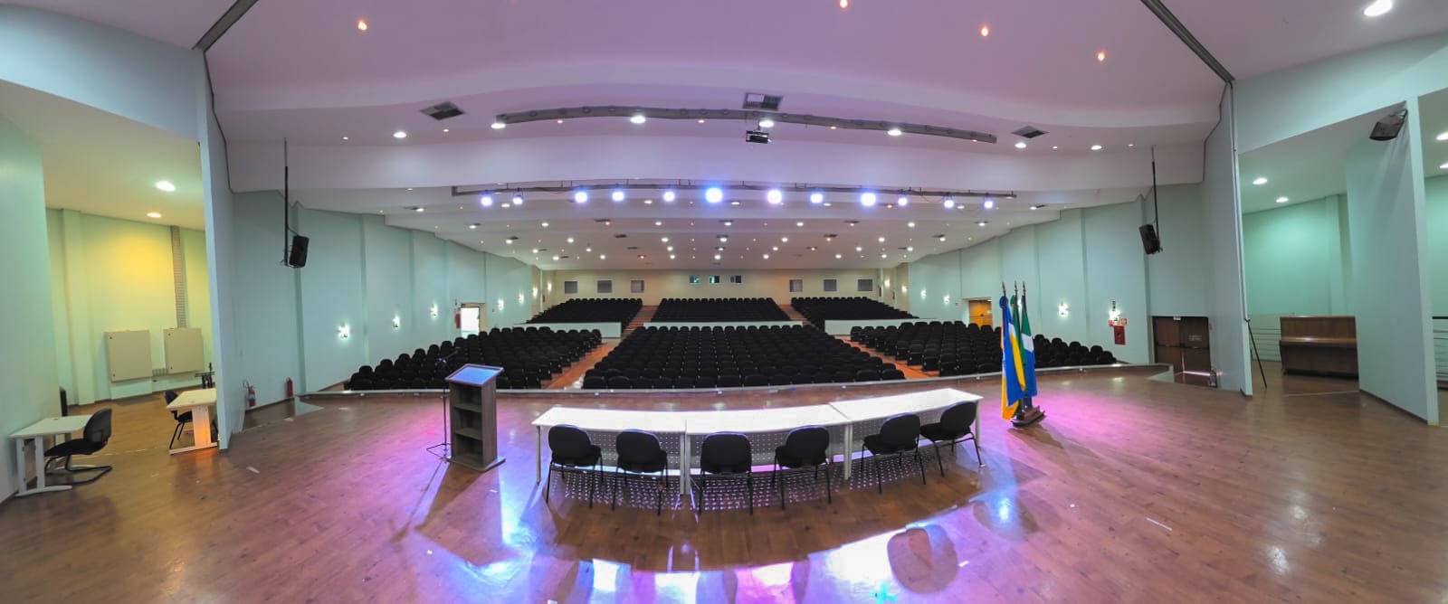 Auditório Central — PALCO COM MOBILIÁRIO, TRIBUNA, PANÓPLIA, BANDEIRAS, PONTOS DE REDE, TELÃO SUSPENSO E DATASHOW SEM FIO.